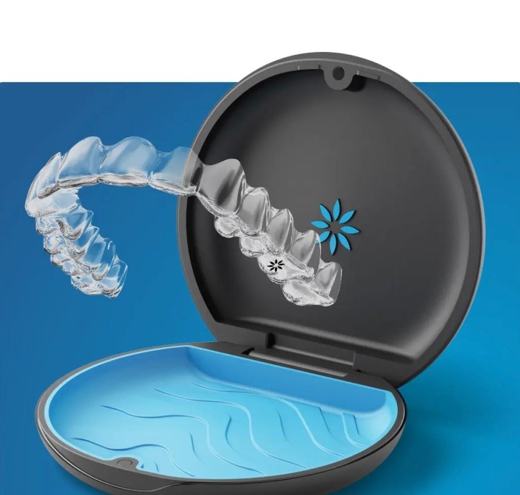 Clear dental aligner being placed into a round, open storage case with a blue interior.