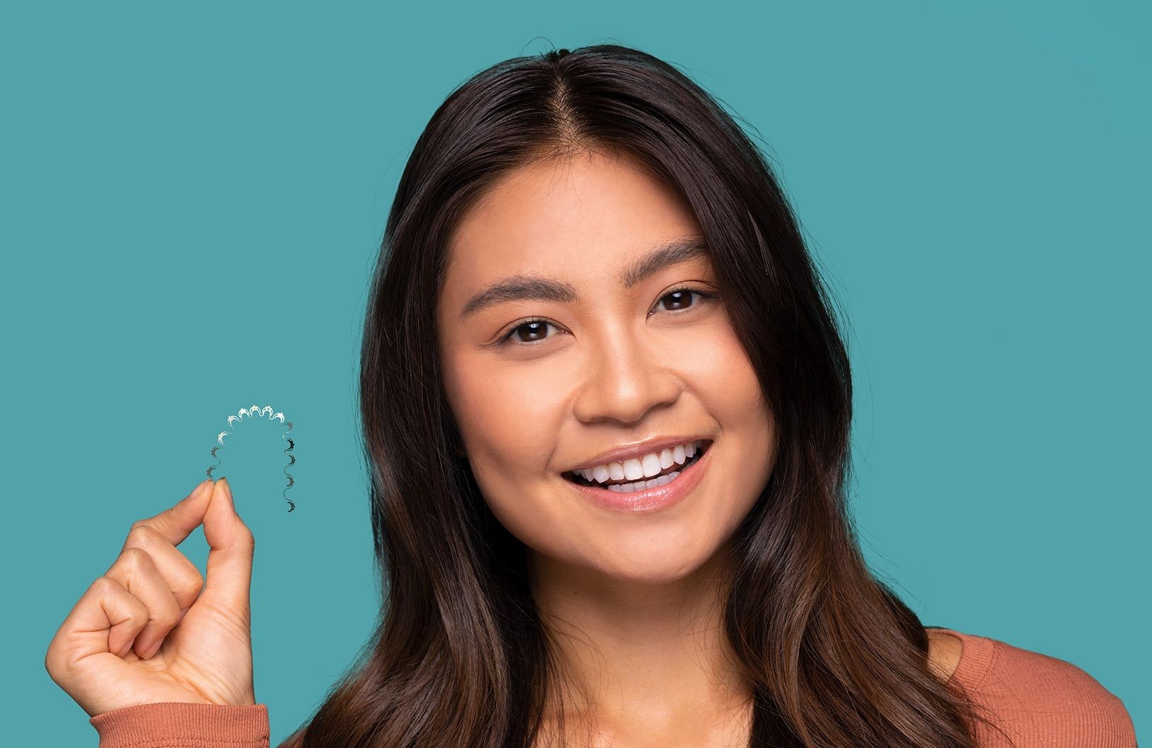 A woman holding an InBrace Smartwire, a custom orthodontic arch wire for lingual braces.